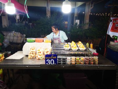 Chiang Rai, Tayland - 12 Haziran : 12 Haziran 2019'da Chiang rai, Tayland'da gece yürüyüş sokak pazarında Tay geleneksel tatlılar satan kimliği belirsiz kadın.