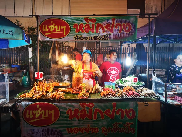 CHIANG RAI, TAILANDIA - 12 DE JUNIO: Personas no identificadas que venden calamares a la parrilla en el mercado callejero nocturno el 12 de junio de 2019 en Chiang rai, Tailandia . —  Fotos de Stock