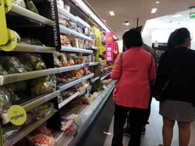 Londra, Uk - 7 Ekim: Kimliği belirsiz Asyalı müşteri 7 Ekim 2019 'da Londra, Uk' ta süpermarkette taze sebze arıyor..