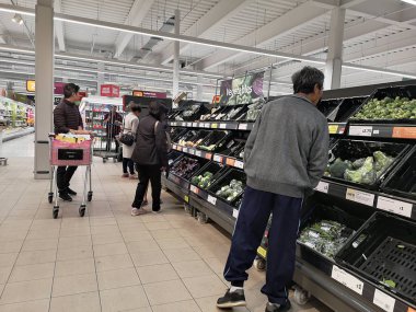Londra, Uk - 7 Ekim: Kimliği belirsiz Asyalı müşteri 7 Ekim 2019 'da Londra, Uk' taki süpermarkette taze sebze reyonuna bakıyor.