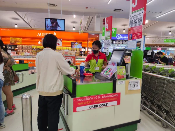 CHIANG RAI, THAILAND - 9 Haziran 2020 'de Chiang Rai, Tayland' da kimliği belirsiz bir Asyalı kadın kasiyerin masasında duruyor..
