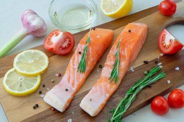 Kesme tahtasında baharat ve sebzelerle pişirmek için somon bifteği. Sağlıklı beslenme, Akdeniz diyeti konsepti. Yatay oryantasyon. seçici odak. 