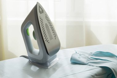 Elektrikli ütü, ütü için hazırlanmış erkek gömleğinin ütü masasının üzerinde dikilir. Ev işi, ev işi, çamaşır konsepti. Yatay yönelim, seçici odak.