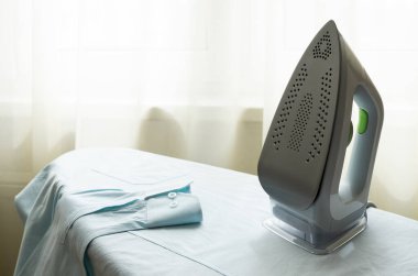 Elektrikli ütü, ütü için hazırlanmış erkek gömleğinin ütü masasının üzerinde dikilir. Ev işi, ev işi, çamaşır konsepti. Yatay yönelim, seçici odak.