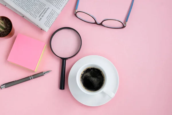 コーヒーカップ グラス 虫眼鏡 サボテン ペンと朝の新聞のピンクの背景にフラットレイアウト 水平方向 選択的焦点 上からの眺め コピースペース — ストック写真