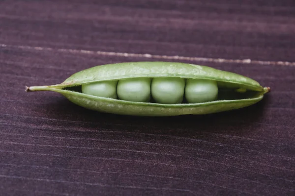 在木制表面隔离的特写鲜绿色豌豆 — 图库照片