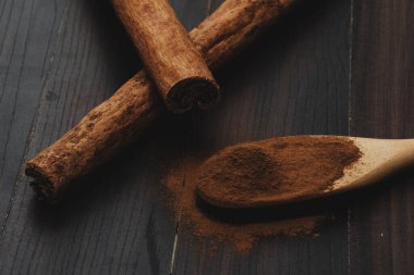 Tarçın çubukları ve ahşap kaşıkta tarçın tozu.