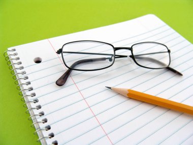 Gözlük, astarlı boş beyaz kağıt ve kalem
