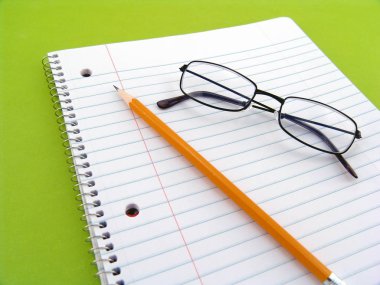 Gözlük, astarlı boş beyaz kağıt ve kalem