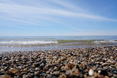 Kıyı üzerinde çakıl ve plaj üzerinde göl kenarında dalgalar ile parlak güneşli gün yıkama su