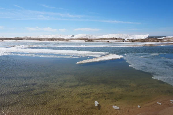 春日的湖岸 水中有冰雪 背景是蓝天 — 图库照片