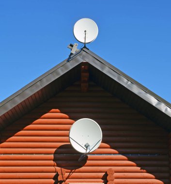 İki Tv Uydu çanakları duvar ve çatı mavi gökyüzü karşı ahşap günlük ev