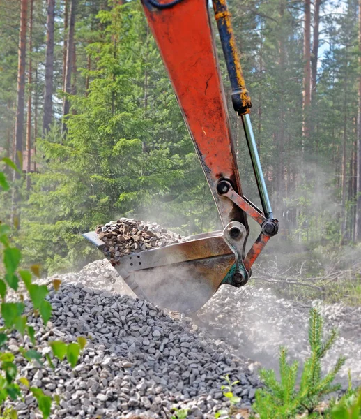 Excavator bucket lifting crushed stone — Stock Photo, Image