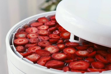 Yemek kurutma makinesinde dilimlenmiş çilek. Dehidratör tepsisinde çilek kesin. Yakın çekim, seçici odak
