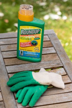 Paris, France - August 15, 2018 : Herbicide on a wooden table in a french garden. Roundup is a brand-name of an herbicide containing glyphosate, made by Monsanto Company. clipart