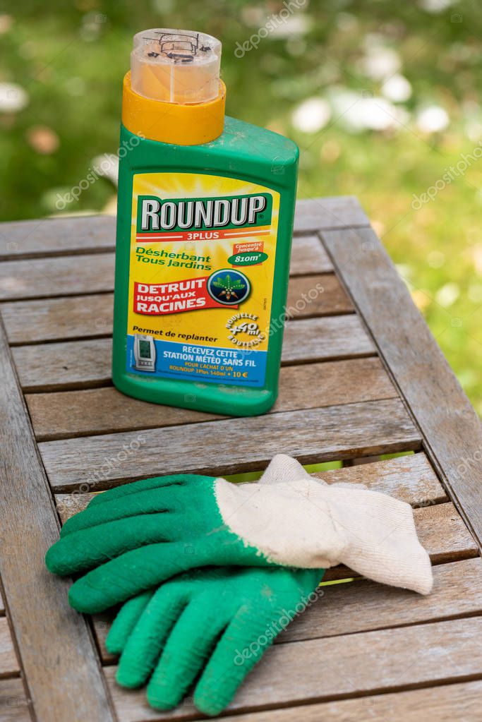Paris, France - August 15, 2018 : Herbicide on a wooden table in a french garden. Roundup is a brand-name of an herbicide containing glyphosate, made by Monsanto Company.