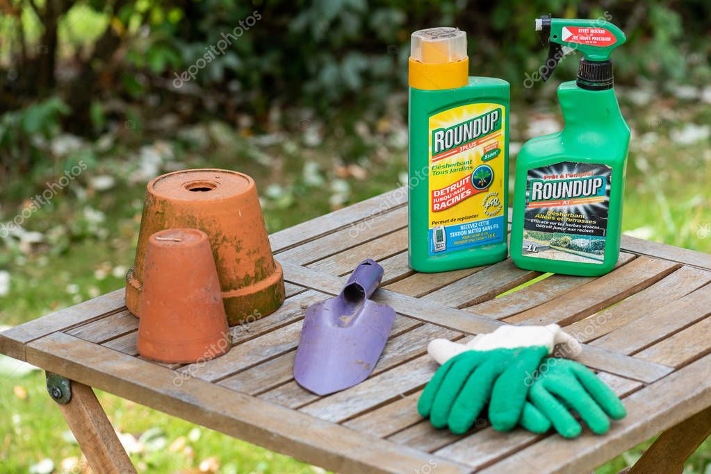 Paris, France - August 15, 2018 : Herbicide on a wooden table in a french garden. Roundup is a brand-name of an herbicide containing glyphosate, made by Monsanto Company.