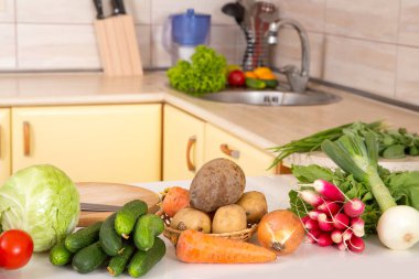 Taze mevsimlik sebze salatası veya diğer sebze yemekleri Mutfak masasının üzerinde. Lahana, domates, salatalık, soğan, turp, pancar, havuç - vejetaryen yemek.