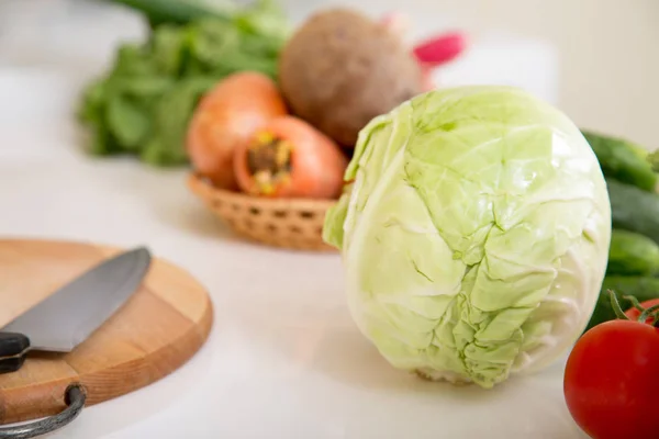 Fresh seasonal vegetables for salad or other vegetable dishes. Knife, cabbage, tomato, cucumber, onion.