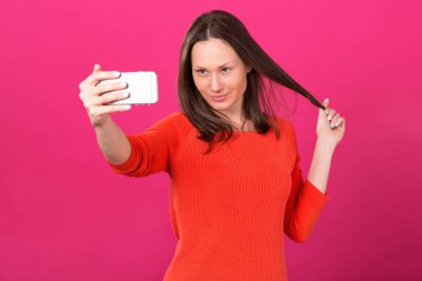 Pembe bir arka plan üzerinde telefon durarak selfie portre yapıyor kadın esmer.