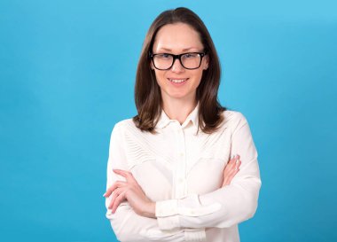 Portre işkadını. Mavi arka plan üzerinde gözlüklü esmer kadın. Kameraya bakarak.