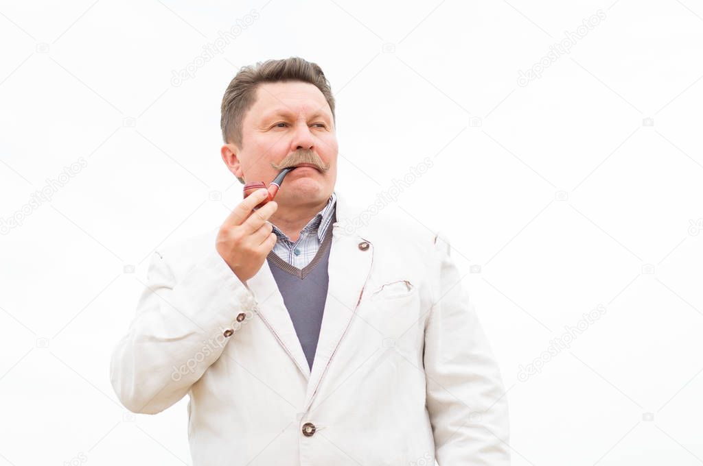 Adult serious man smokes a pipe.