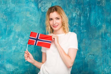 Norveç bayrağı mavi duvar arka plan üzerinde mutlu sarışın kadın.