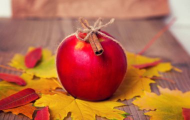 Kırmızı elma sonbahar ile ahşap bir masa üzerine tarçın yalanlarla bırakır.