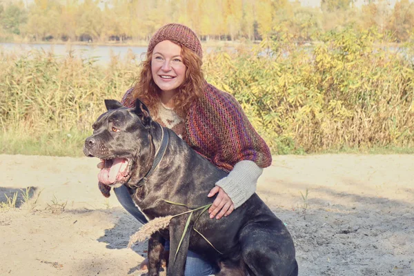Woman playing with her big dog at park. Autumn. Lifestyle and friendship concepts.