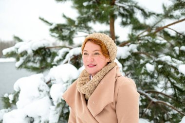 Kış zamanında mutlu bir kadın. Kadın bir arka plan yeşil çam karda bir kış günü açık havada.