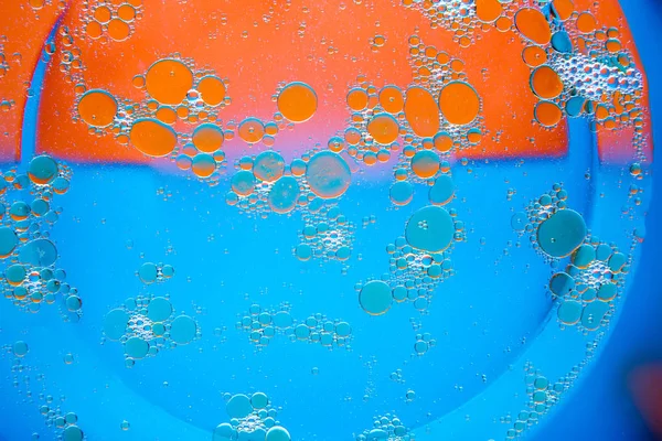Circles of oil on water blue orange background. Abstract background for text.