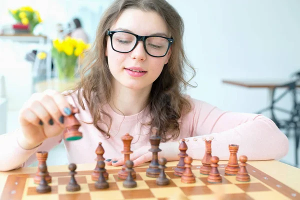 Young woman is playing chess. Chessmen.