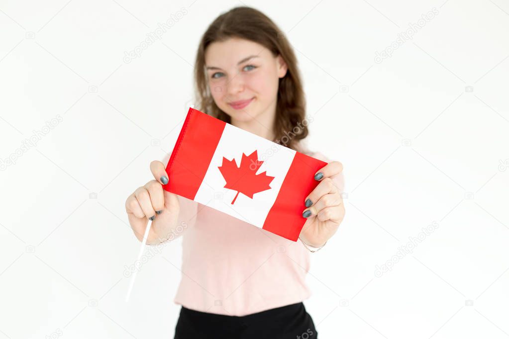 Flag of Canada in the hands of close-up. Young girl with the flag of Canada in hands. Her face is blurry not in focus.