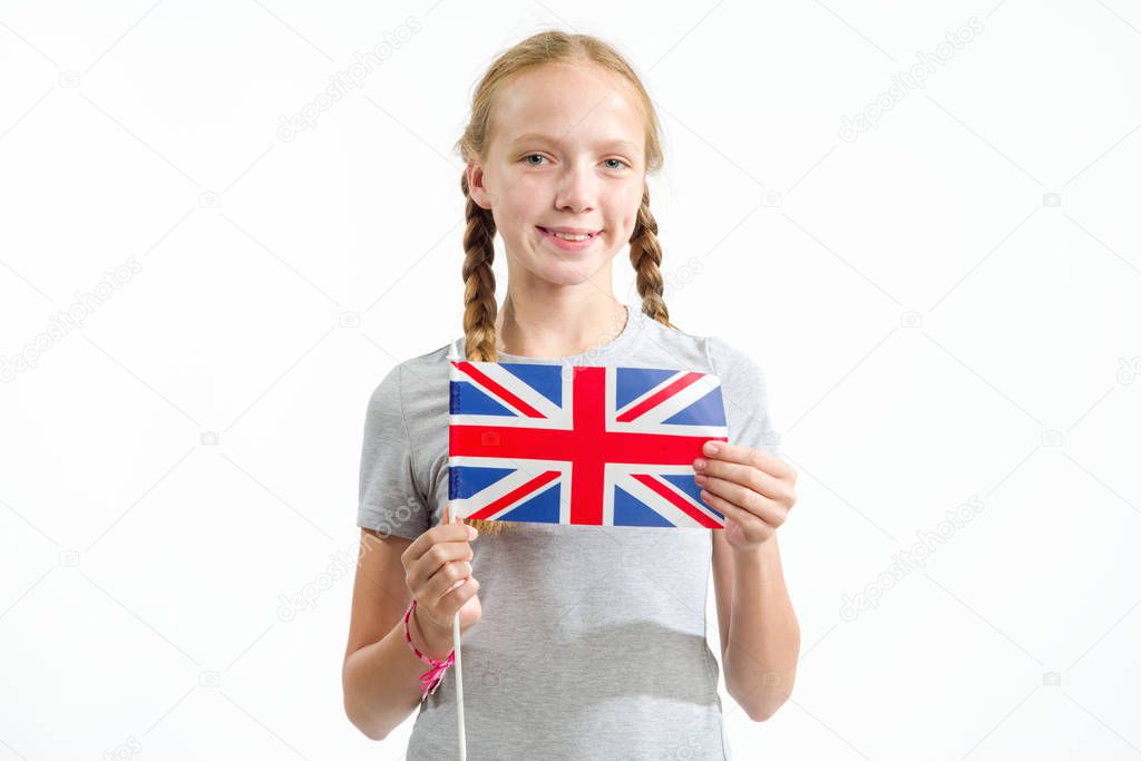 Beautiful teenager girl under the flag of Great Britain on a light background. Learn English.
