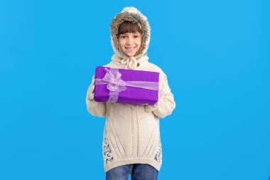 Ellerinin üzerinde mavi bir arka plan mor hediye kutusunda küçük kız. Noel tatil hediye.