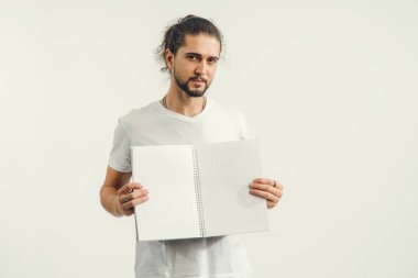 Genç erkek öğrenci önünde boş çarşafları ile açık bir defter tutuyor.