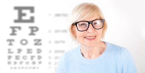 視力検査で目のこと メガネの年配の女性の肖像画は バック グラウンドをテーブル にします 医師の眼科医を訪問 — ストック写真