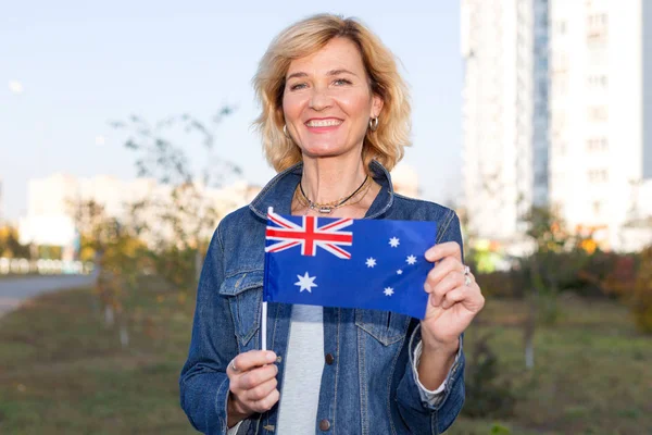 Mature woman with Australia flag on city and blue sky background.