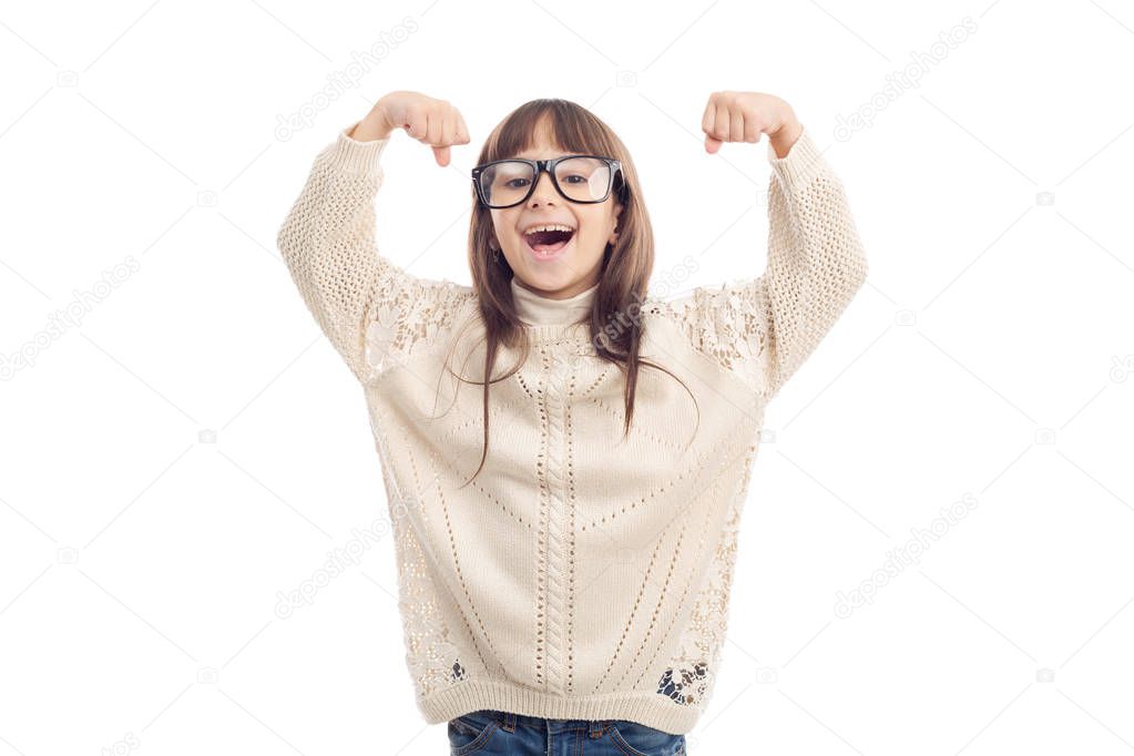Cheerful little girl with glasses shows with her hands that she is strong.