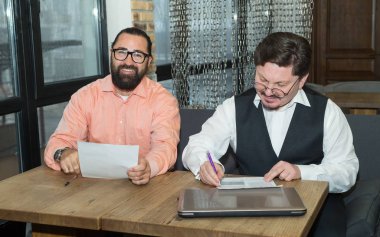 İki olgun iş adam belgeleri bir ofiste bir masada oturan bir satınalma veya satış kişi üzerinde tartışmak. Günlük iş akışı.