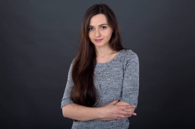 Gri bir arka plan üzerinde uzun saçlı esmer bir kadın portresi.