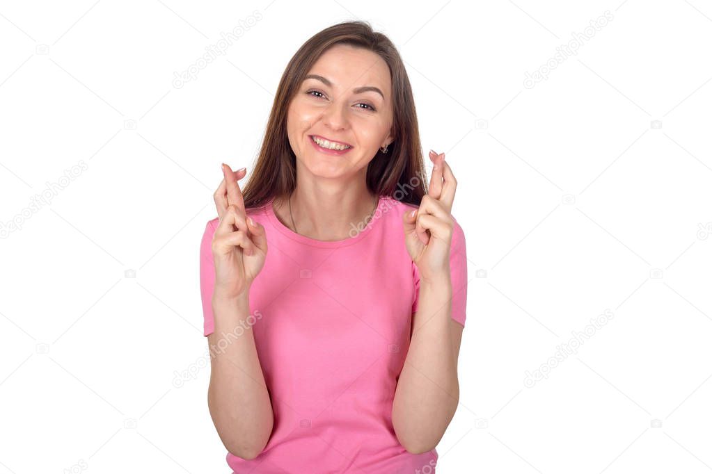 Young girl crossed her fingers for good luck. Portrait of a happy brunette woman with long hair on a white background.