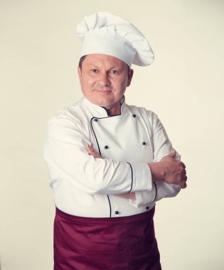 Olgun erkek aşçı portresi yemek hafif sarı arka plan üzerinde bir üniformalı. Renkli fotoğraf.