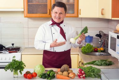 Olgun erkek aşçı taze sebze diyet yemek hazırlanıyor. Şef mutfakta yiyecek hazırlar.