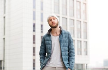 Bir ceket ve şapka arka planı şehrin modern genç bir adam portresi.