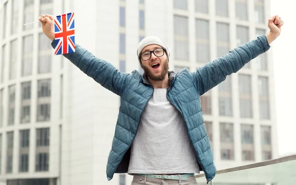 Happy young man in glasses with flag of Great Britain against the background of the city. Champion, football fun. Learning English.