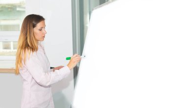 Genç kadın ofiste girişleri için bir beyaz tahta üzerinde yazıyor. Sunu sırasında bir iş kadını. Beyaz tahta veya metin reklam bilgilerini kaydetmek için.