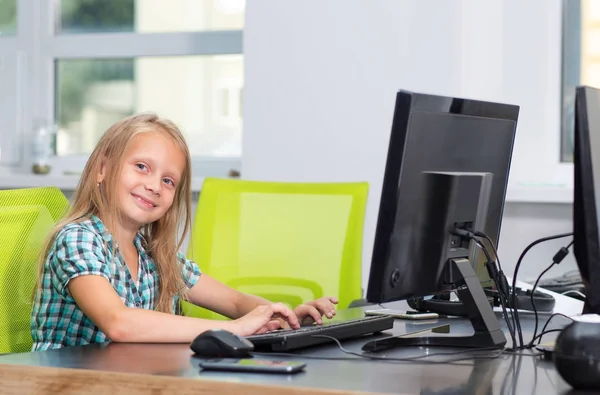Little girl 7 years old works behind a computer. Online education. Computer courses for children.