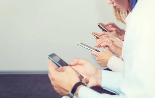 Grup dört kişi cep telefonlarında bak. Yeni teknoloji trendleri ofis personel bağımlılığı. Sosyal ağ Smartphone kullanarak kavramı iş adamları. Haberler ve döviz kurları, ticaret izleyin.