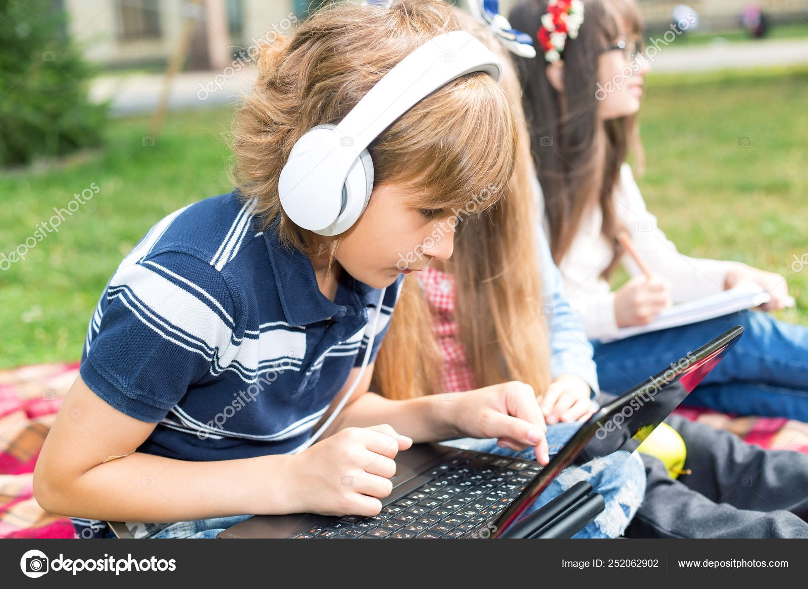Um menino com fones de ouvido está sentado em um computador